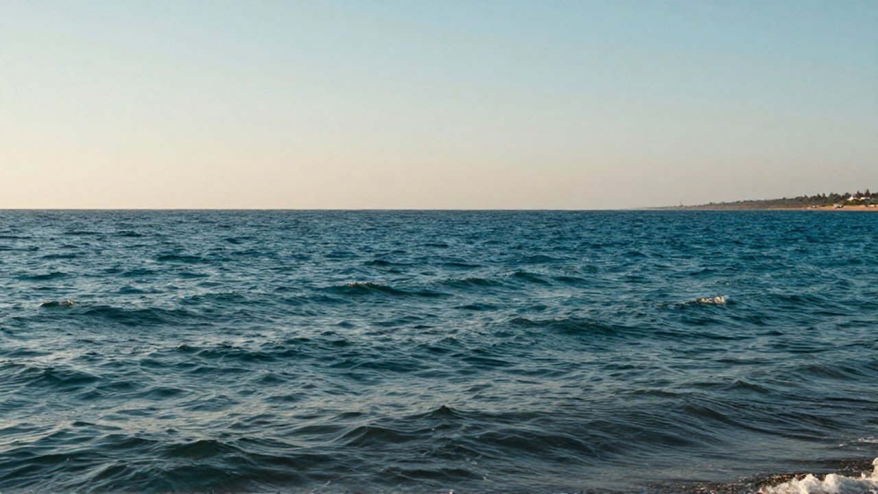 Océano de tonos azules y turquesas con olas suaves bajo la luz cálida del atardecer.